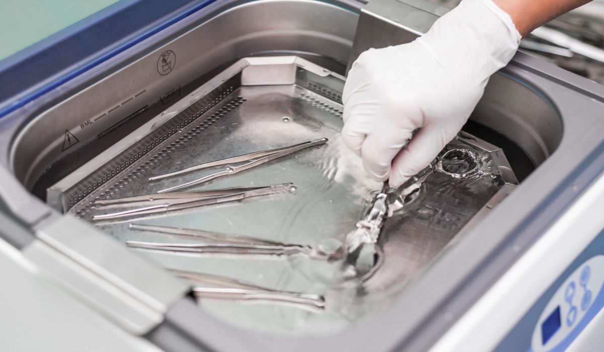 Manos depositando instrumentos quirúrgicos en máquina autoclave